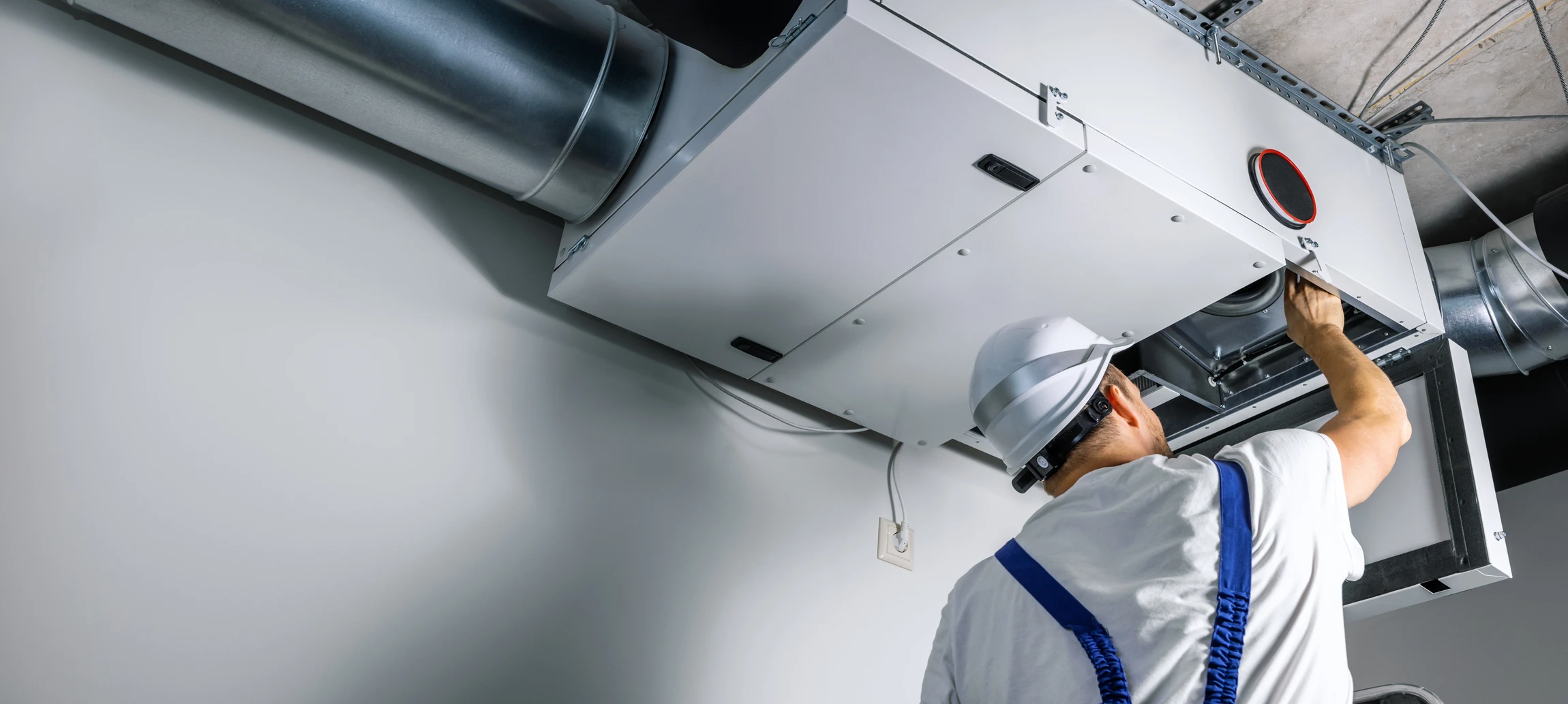 Installateur en gants de protection blancs et bleus positionnant une grille d'aération ventilation dans plafond blanc d'intérieur résidentiel