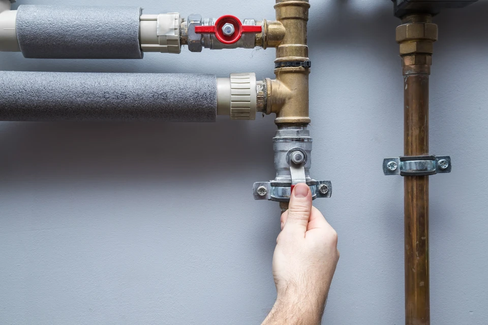 Main tenant ouvre une vanne de canalisation dans un local technique intérieur